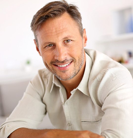 Man in collared shirt sitting at table and smiling