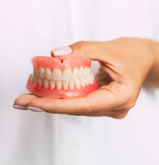 dentist holding set of full dentures 
