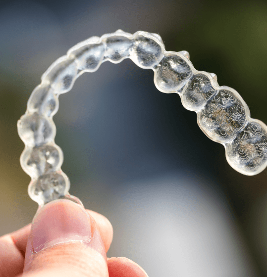 Hand holding a clear Invisalign tray