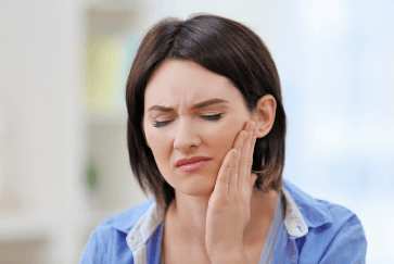 Woman in need of restortive dentistry holding jaw