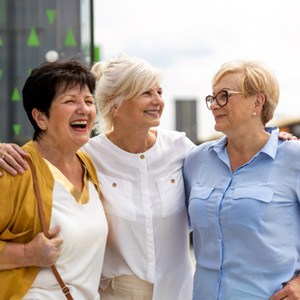 Three women smiling while hugging outside