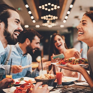 Group of friends smiling while eating at restaurant